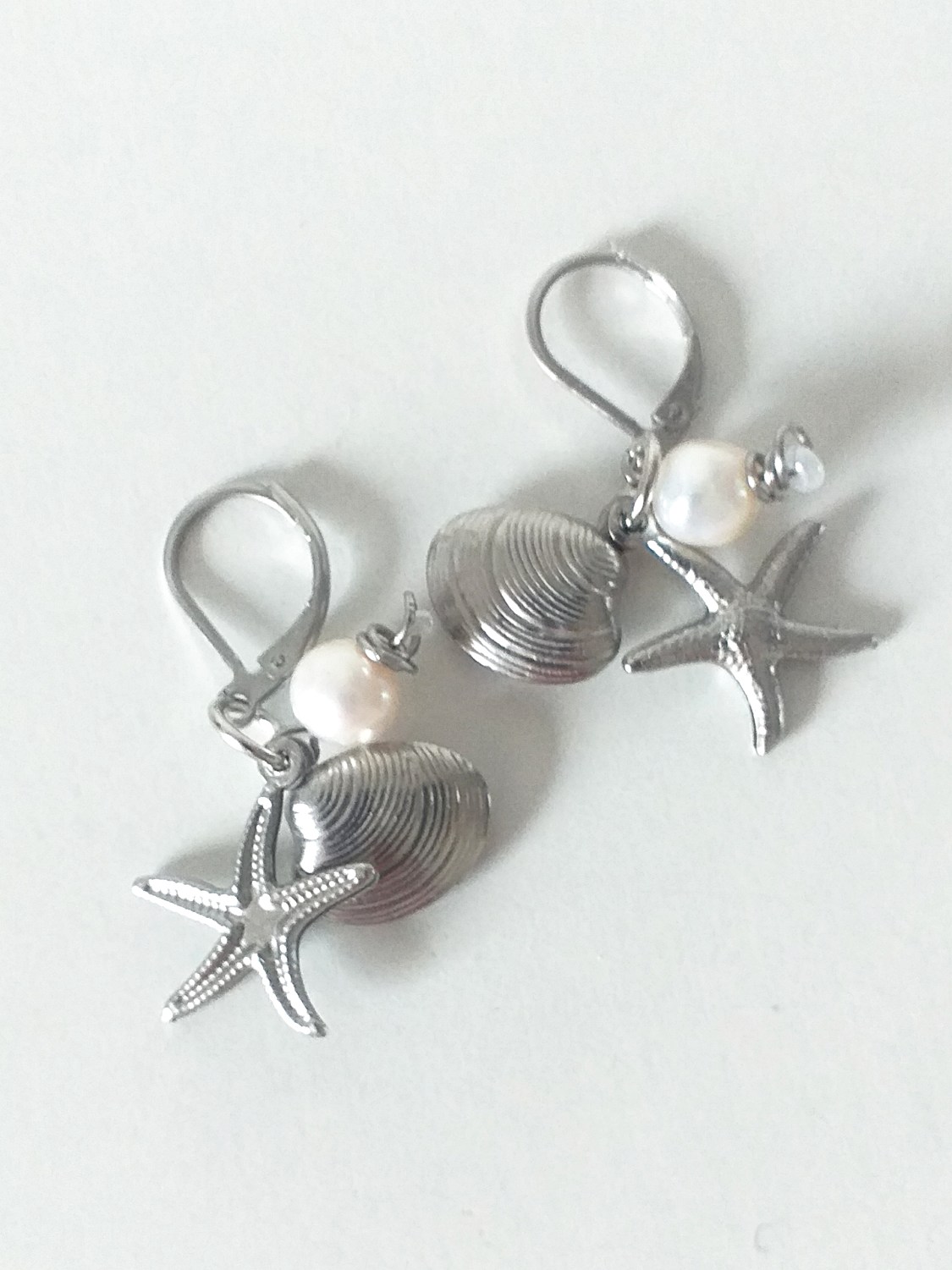 Sølvfarvede øreringe med strandskaller